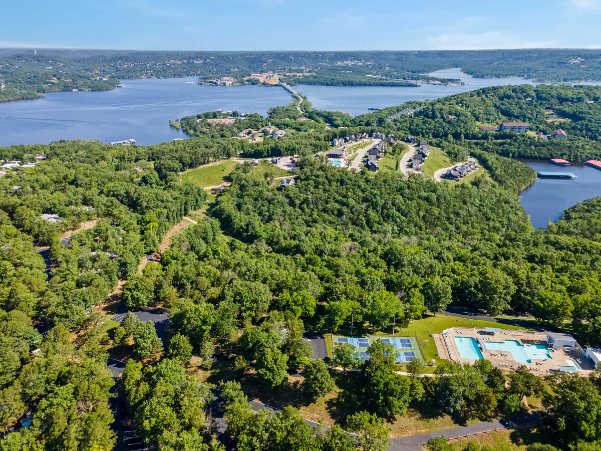 This image showcases lush greenery, a swimming pool, tennis courts, water features, and residential areas, all set in a tranquil, natural resort landscape. Paths and open spaces suggest plenty of room for outdoor activities and exploration.