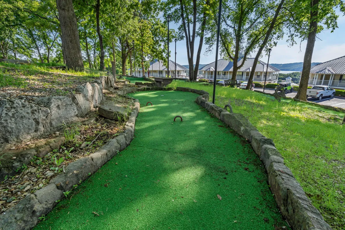 A vibrant exterior view of the resort's mini-golf course nestled among lush greenery and tall trees. The playful paths and colorful obstacles are visible, inviting families to enjoy a round of mini-golf together in a natural setting.