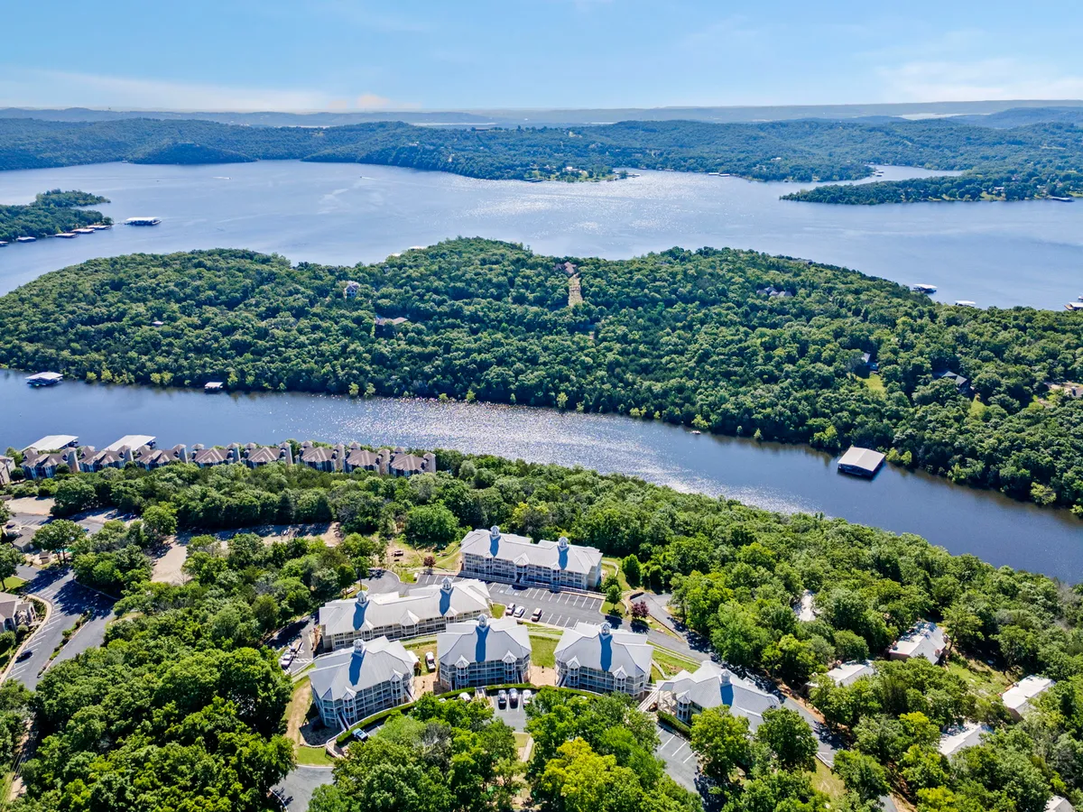 A broad lake view with green hills and residential buildings on the shore, conveying a sense of open space and scenic tranquility. The area is perfect for lakeside walks, picnics, and relaxing with pets.