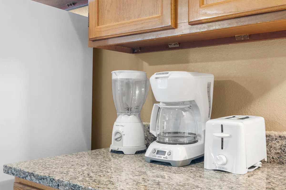 A close-up of a kitchen counter displaying a blender, coffee maker, and toaster, emphasizing thoughtful amenities for breakfast and morning rituals. The setting feels cozy and practical, signaling attention to daily comfort.